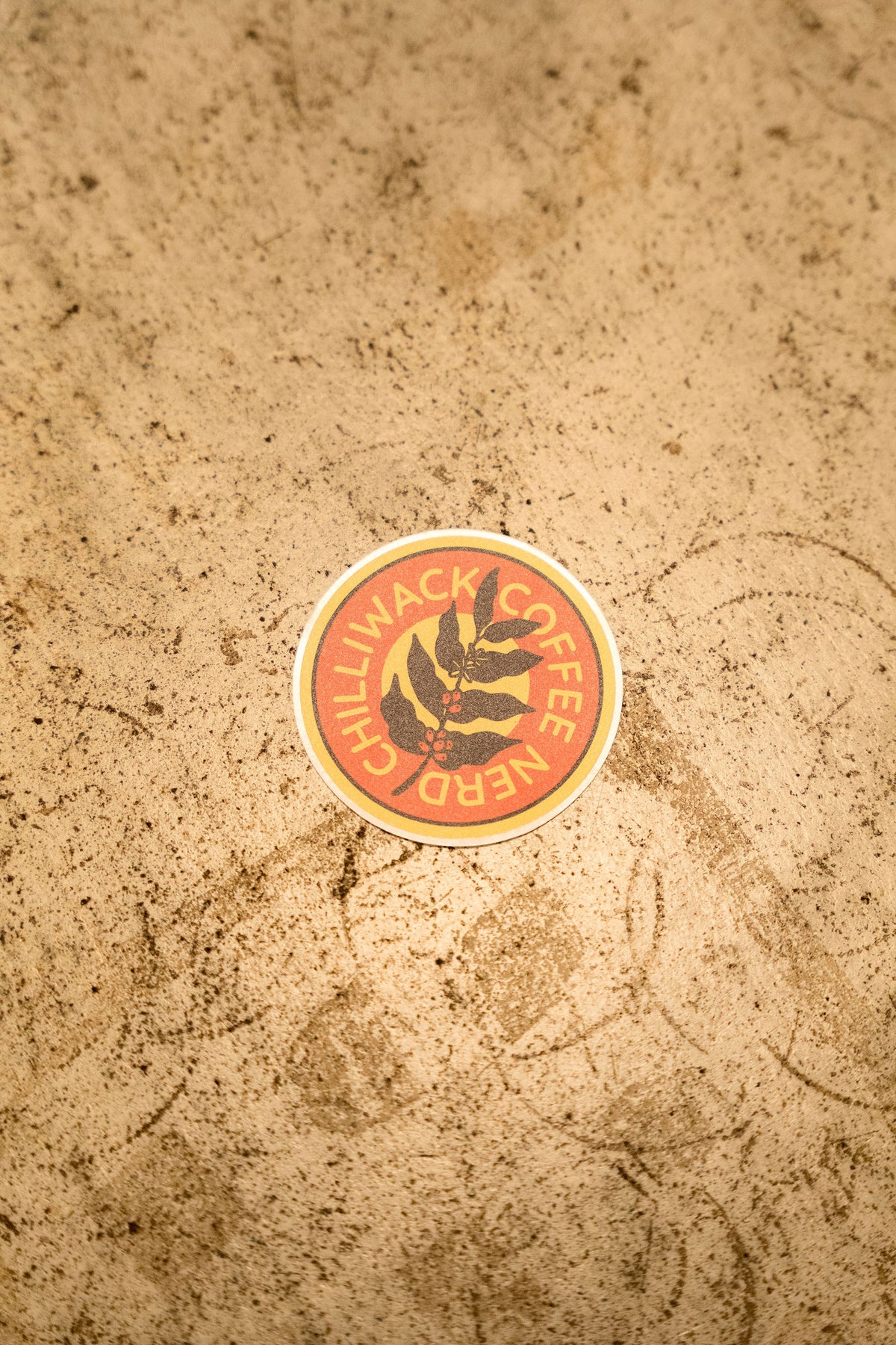 Chilliwack Coffee Nerd round sticker on a stone counter